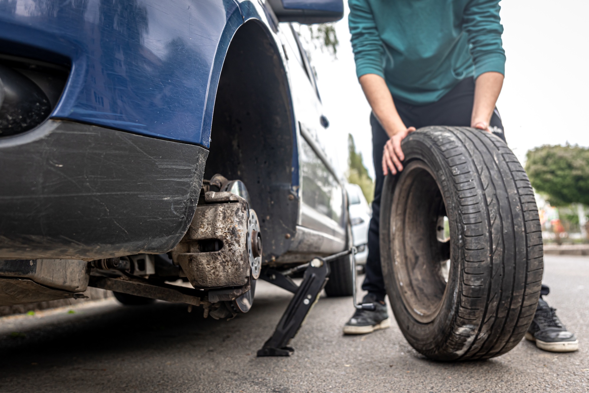 Close-up a man changes a tire in a car on the road.